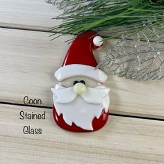 a santa clause ornament sitting on top of a wooden table next to a pine tree