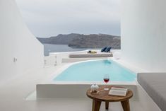 a table with a glass of wine next to a swimming pool on the side of a building