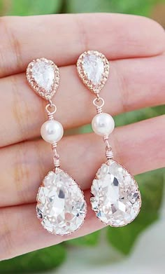 a pair of earrings with pearls and crystal stones on the end of each droplet