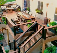 an outdoor deck with patio furniture and umbrellas on the top floor, surrounded by greenery