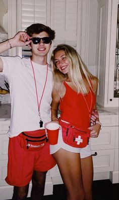 two people standing next to each other wearing red and white outfits, one holding a cup