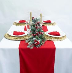 the table is set for christmas dinner with red napkins and gold placemats