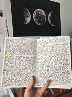 an open book with writing on it and three phases of the moon in the background