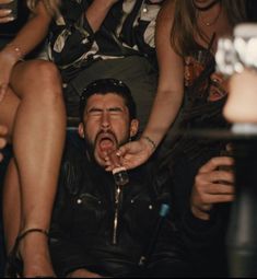 a man sticking his tongue out while sitting in front of other people at a party