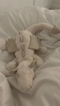 a white stuffed animal laying on top of a bed