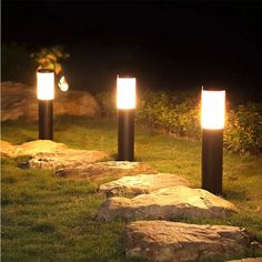 three lights that are on some rocks in the grass