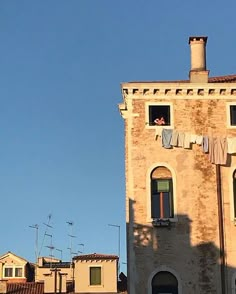 an old brick building with clothes hanging out to dry on the windows and in front of it