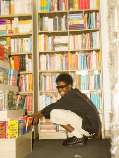 a woman kneeling down in front of a bookshelf filled with lots of books