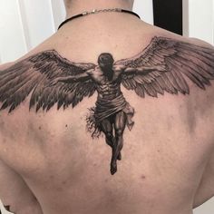 the back of a man's upper body with a cross and angel tattoo on it