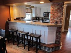 a kitchen with an island and three stools in it, along with a dining room table