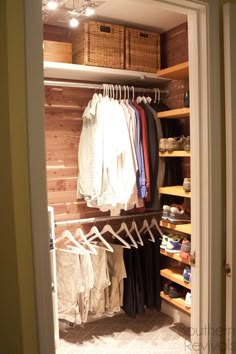 an open closet with clothes and baskets on the shelves