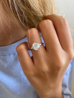 a woman's hand with a diamond ring on her left side, wearing a blue shirt