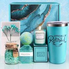 a blue gift box containing a candle, teal candles, and other personal care items