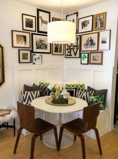 a dining room table with chairs and pictures on the wall above it, along with two benches