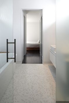 an open door leading to a bedroom with a bed and bathtub in the background