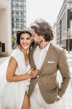 a man in a suit and tie standing next to a woman wearing a white dress