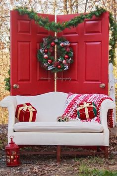 a white couch sitting in front of a red door with christmas decorations on top of it