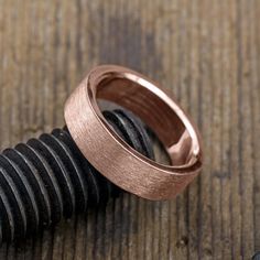 two wedding rings sitting on top of a wooden table next to a black and white screw