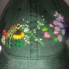 a green hat with embroidered flowers on it