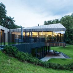 the house is surrounded by lush green grass and has a large deck on one side