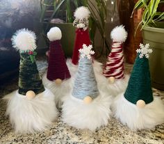 four knitted christmas hats with pom poms on the top and one in the middle