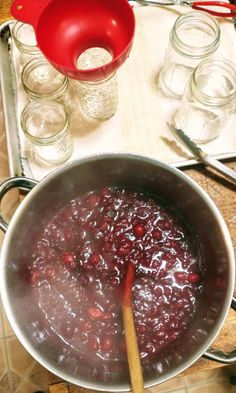 a pot filled with cranberry sauce on top of a stove next to utensils