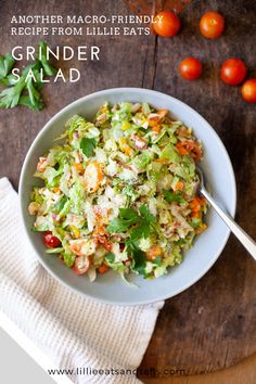 a white bowl filled with salad on top of a wooden table next to cherry tomatoes