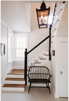 a black chair sitting under a light on top of a wooden stair case next to a white door