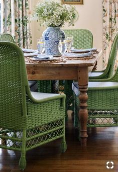 a dining room table with green chairs and a blue vase on top of the table