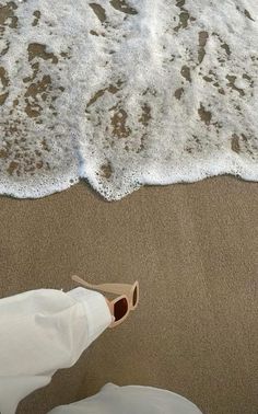 a person standing on the beach with their feet in the sand