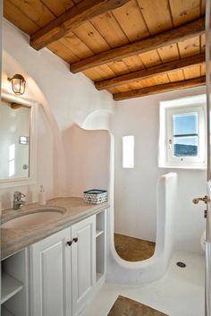 a bathroom with white walls and wooden ceiling