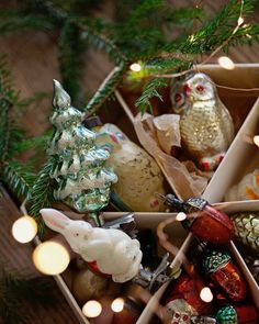 an open box filled with christmas ornaments on top of a wooden table next to a tree