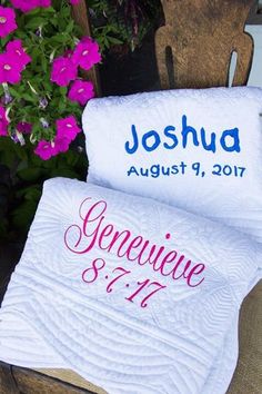 two personalized towels sitting on top of a wooden chair next to flowers and potted plants