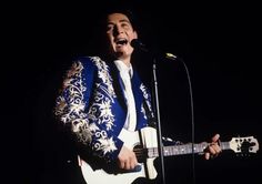 a man singing into a microphone while holding a guitar