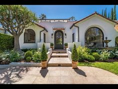 a white house with lots of windows and plants