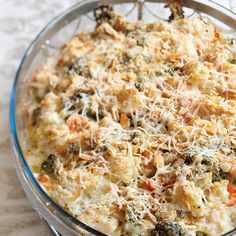 a casserole dish with broccoli, cheese and other toppings in a glass bowl