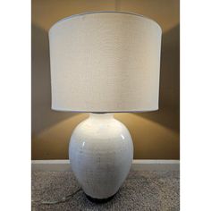 a large white vase with a light on it's side in front of a wall