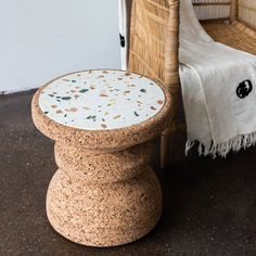 a small stool sitting on top of a floor next to a wicker chair and rug