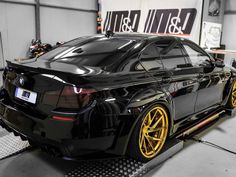 a black car parked in a garage with yellow rims on the front and sides