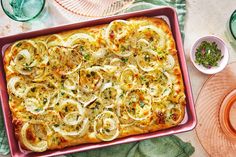 a casserole dish with onions and herbs on a pink tray next to other dishes