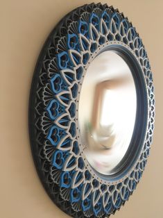 a circular mirror hanging on the wall with blue and white designs in front of it