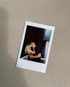 a polaroid photograph of a woman leaning on a railing with her head in her hands