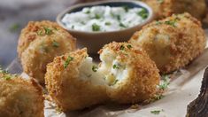 some fried food is on a plate with dip and sour cream in the bowl next to it