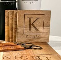 wooden cutting boards with the letter k on them next to bottles of wine and scissors