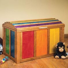 a wooden toy chest sitting on top of a hard wood floor next to stuffed animals