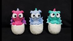 three crocheted dragon slippers sitting on top of a black cloth covered surface