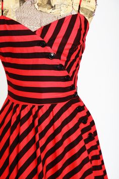 "Sweet vintage 1970s does 1950s striped full skirt midi dress Lightweight black + red cotton Asymmetrical button down side pull over fit with single pocket Excellent condition M e a s u r e m e n t s: Size: vintage sz. 4 - fits like XS Bust: 16\" Waist: 12 1/2\" Hips: open Total Length: 40\" Label: Popi Fabric: cotton +All Measurements are taking while garment is lying flat+ + Jewelry, belts, and any other accessories are NOT included unless specifically stated in description + i n s t a g r a m Retro Striped Lined Dress, Striped Retro Dresses With Buttons, Retro Striped Dresses With Buttons, Retro Striped Midi Dress, Flat Jewelry, Vintage Striped Dress, Full Midi Skirt, Full Skirt Dress, 1980s Dresses