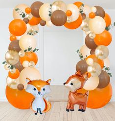 an orange and white balloon arch with two foxes