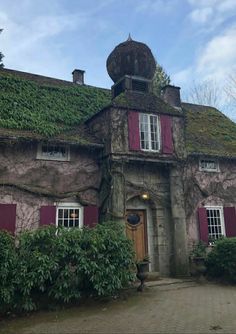 an old house with red shutters and ivy growing on the roof