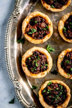 mini meat pies on a silver platter with parsley garnishes